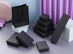 Various sizes of black kraft paper jewelry gift boxes with matching handles on a purple base