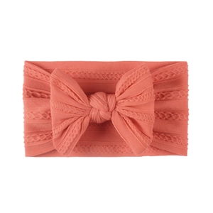 Close-up of soft jacquard nylon baby headband with a large coral pink bow knot