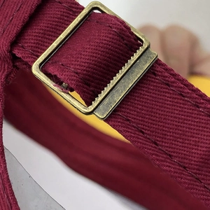 Détail de la sangle en toile bordeaux avec boucle en métal bronze et texture antidérapante