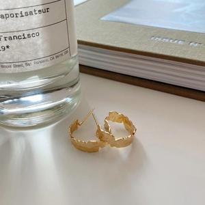 Close-up of gold irregular hammered studs on a minimalist white surface background
