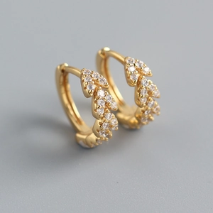 Macro detail of gold hoop earrings with leaf design and micro-pave cubic zirconia