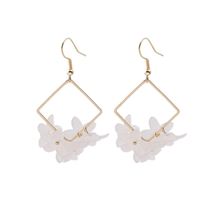 Detail of white translucent daisy flower earrings with gold geometric square frame
