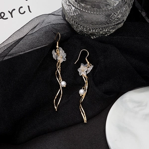 Detailed shot of white floral petal earrings with pearls on a black mesh fabric background
