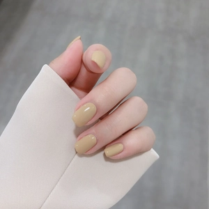 Short minimalist solid beige glossy press-on nails shown with beige suit sleeve
