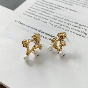Detail of gold textured S925 silver earrings with pearls displayed on a white magazine
