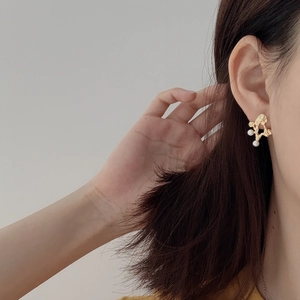 Detail of gold irregular textured stud earring with white pearls worn by model