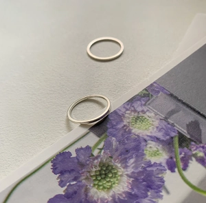 Detail of minimalist 925 sterling silver square band rings on aesthetic floral card