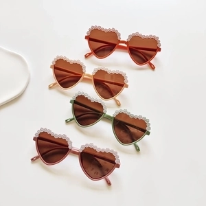 Stylish heart-shaped kids sunglasses with lace trim in earthy tones on white background