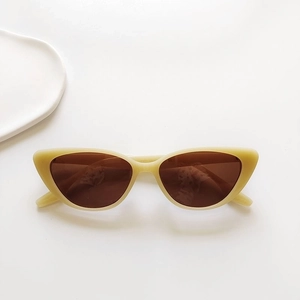 Detailed close-up of cream retro cat-eye sunglasses on a minimalist white ceramic tray