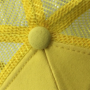 Close-up of bright yellow mesh baseball cap with reinforced stitching and top button