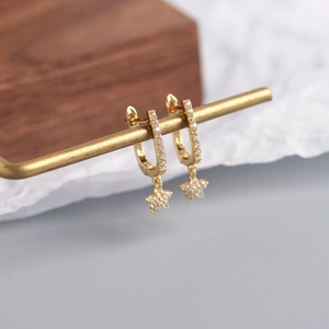 Macro detail of gold U-shaped earrings with crystal-encrusted hexagonal star charms