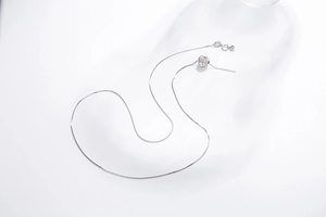 Detail of s925 silver box chain with a round slider bead on a clean white background