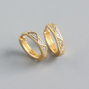 Macro shot of gold-plated geometric earrings with sparkling zircon inlay details