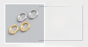 Detailed view of silver and gold hexagonal huggie earrings with CZ stone settings