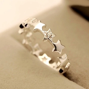 Polished silver star ring with center zircon inlay shown on a beige velvet box