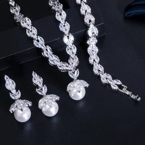 Macro detail of bridal jewelry set with marquise zircon and round pearls on black texture