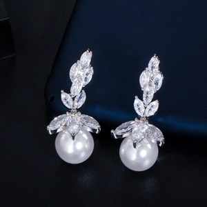 Close-up of bridal marquise-cut zircon earrings with round white pearls on dark background