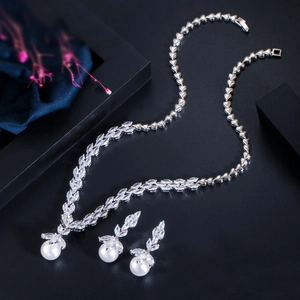 Macro view of bridal jewelry set with marquise zircon, heart chain and pearls on black satin