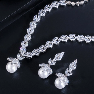 Close-up of bridal jewelry set with marquise zircons and white pearls on black texture