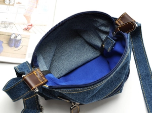 Detail view of denim crossbody bag with bright blue lining and brown leather zipper pull