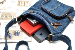 Deep blue denim crossbody bag with brown leather trim showing inner capacity for gadgets