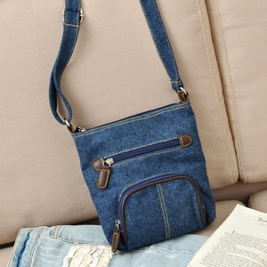 Detailed view of the dark blue denim crossbody bag with yellow stitching and leather puller