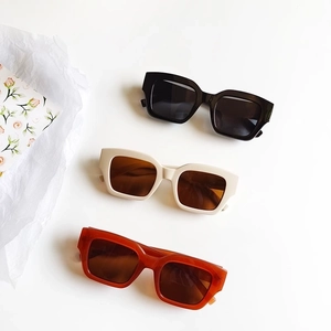 Retro square frame sunglasses in black, beige, and amber brown colors on a white surface
