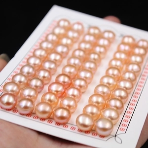Close-up of high-luster pink freshwater button pearls displayed on a white card mount