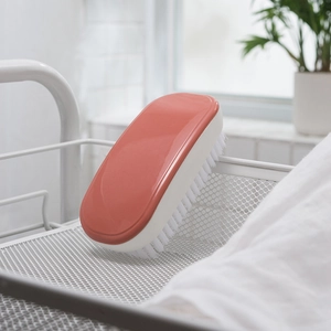 Coral orange laundry cleaning brush with stiff bristles in a minimalist home setting