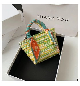 Detail of green and yellow woven handbag with decorative printed silk scarf in a gift box