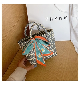 Detail of woven tote bag with grey geometric pattern and orange sunflower silk scarf