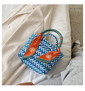 Detail of blue woven handbag with decorative orange silk scarf handle and peace lettering