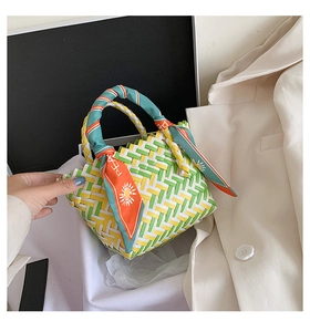 Detail of woven straw tote bag with colorful tricolor texture and silk scarf handle
