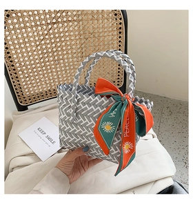 Detail of woven tote bag with geometric pattern and decorative orange floral silk scarf