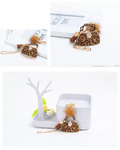Detail of leopard print mini bag charm with gold hardware and plush pompom decor