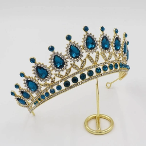 Close-up of golden baroque crown with blue teardrop crystals and clear rhinestones