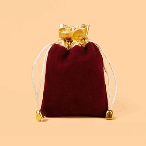 Red velvet drawstring jewelry pouch with golden trim and metallic cord ends