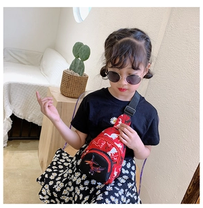 Enfant portant un sac de poitrine dinosaure rouge avec écusson et sangle réglable