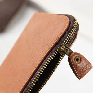 Detail of brown litchi grain leather wallet featuring premium metal zipper and stitching