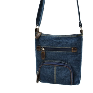 Close-up of blue denim crossbody bag with brown leather strap and metal zipper detail