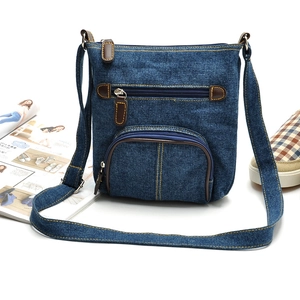 Classic blue denim crossbody bag with multiple front pockets and brown leather zipper pulls