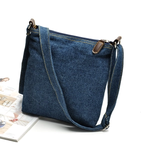 Classic blue denim crossbody bag with brown leather details on a white background