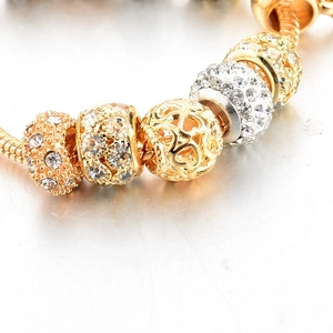Close-up of heart charms and crystal beads on a gold snake chain bracelet