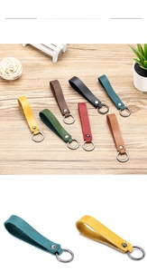Close-up of leather keychains in multiple colors with metallic rings on wooden surface