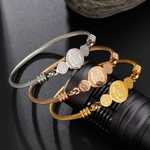 Close-up of tricolor cable bracelets with Virgin Mary religious charms in gold and silver