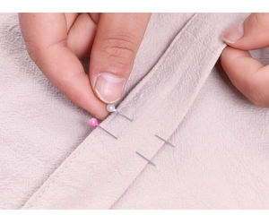 Close-up of pink pearl head pins being used to secure fabric for home sewing projects
