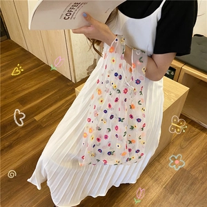 Detailed view of white mesh tote bag with colorful floral embroidery on a female model