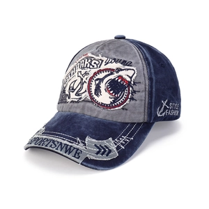 Detail of washed denim baseball cap featuring shark embroidery and vintage frayed brim edges
