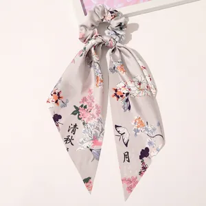 Detail of silk-satin floral hair scrunchie with long ribbons and butterfly print
