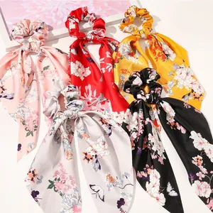 Detail view of satin hair scrunchies with floral prints and long ribbon streamers
